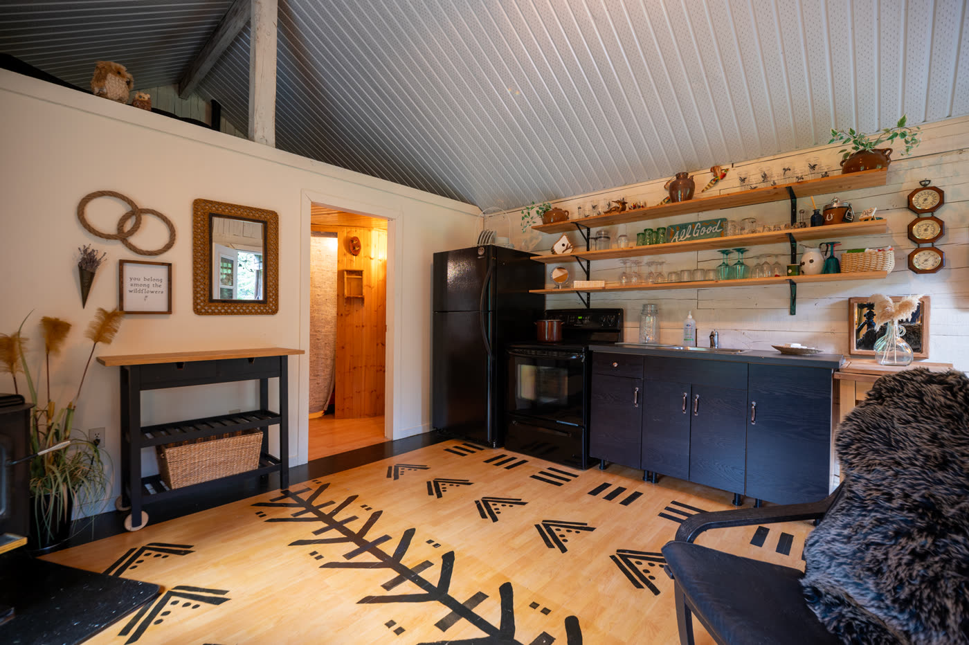 The guest cabin kitchenette, open shelving above a dark counter