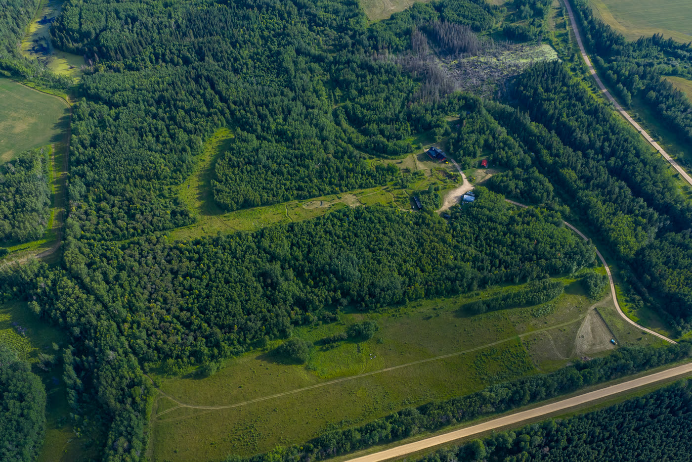 The full property from high above, cleared lanes threading the forest