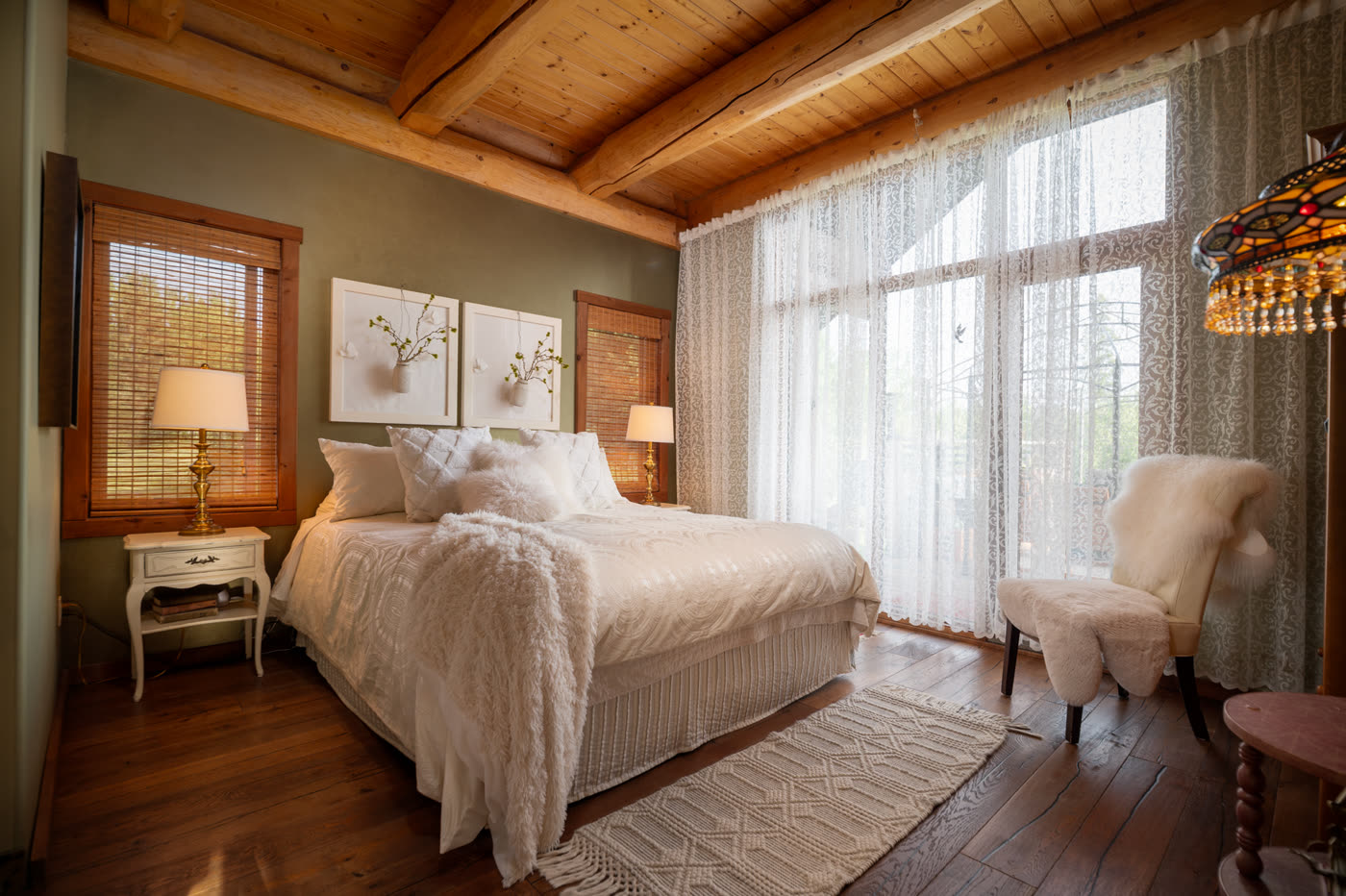 A pale bedroom with sheer curtains and an armchair by the window