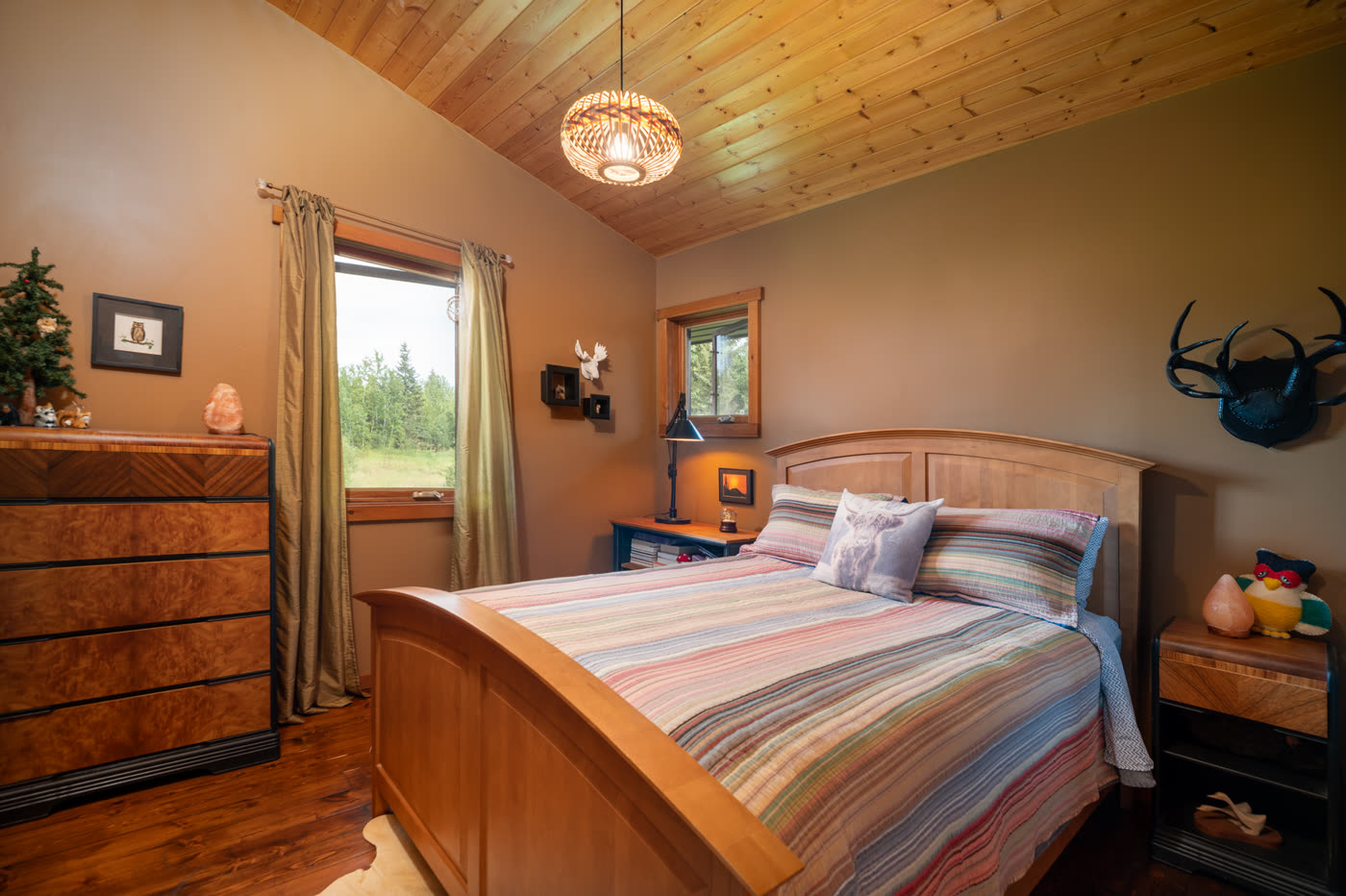 A bedroom with a wooden bed frame and a window onto the field