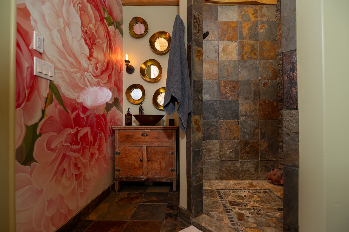 The main house ensuite, a painted peony mural beside a slate walk-in shower