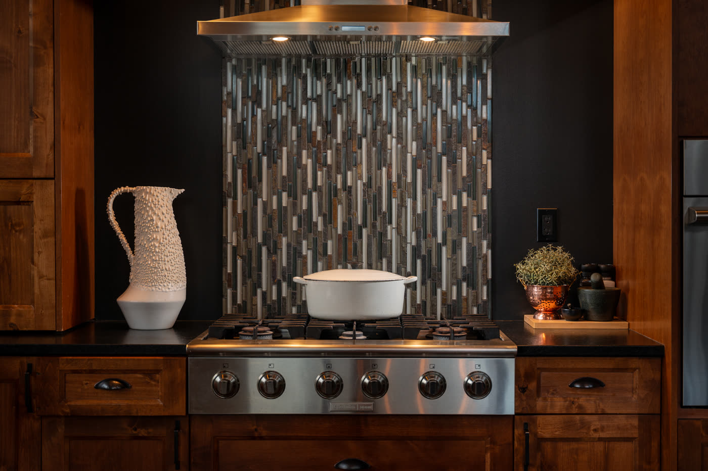 The kitchen range against a tiled backsplash, copper and pottery on the counter